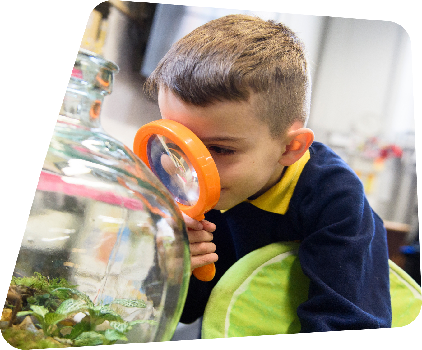 Child with orange magnifying glass looking at jar